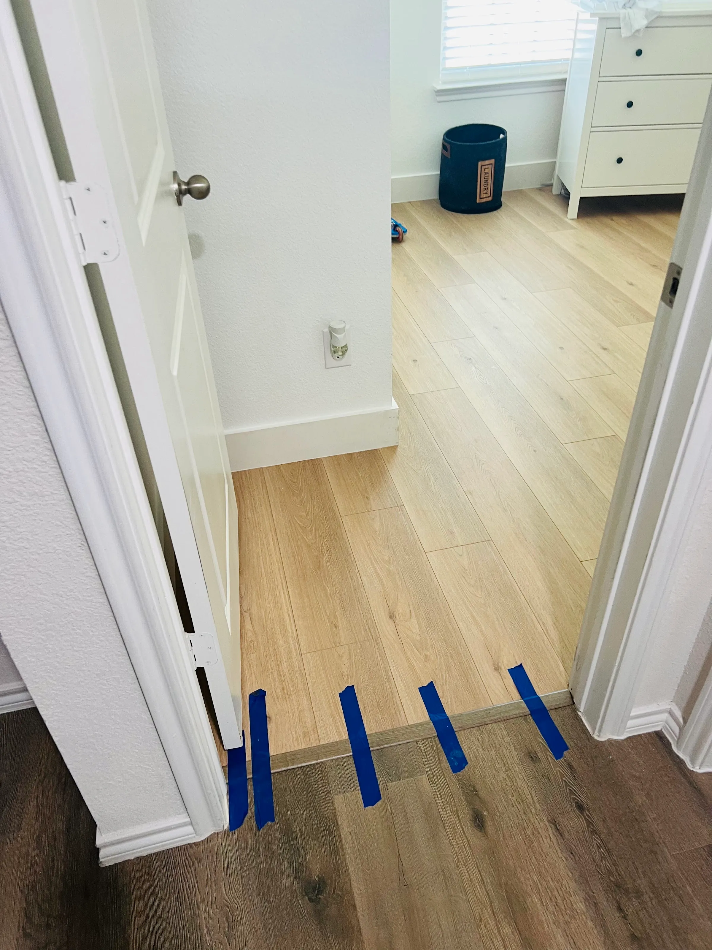 Otra perspectiva de la transición de la puerta, mostrando LVP claro en la recámara que lleva al piso más oscuro del pasillo, con cinta azul en la transición.