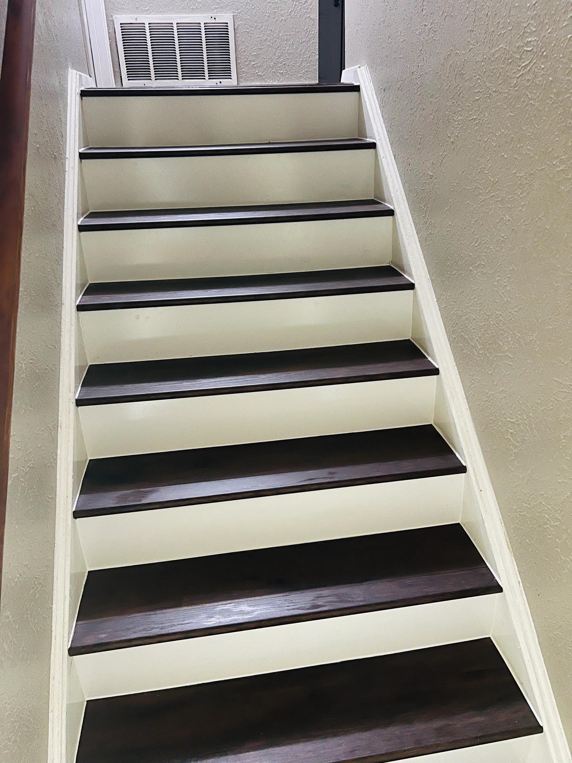 Ángulo ligeramente diferente de la escalera, resaltando las huellas de LVP oscuras y las contrahuellas blancas que se extienden hacia arriba.